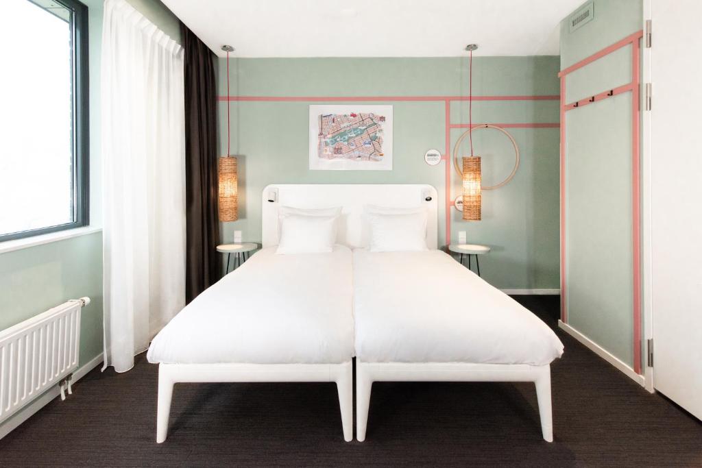 a bedroom with a large white bed with white pillows at Conscious Hotel Vondelpark in Amsterdam