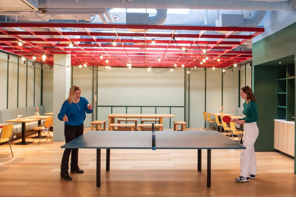 two women standing in a room with a ping pong table at Conscious Hotel Vondelpark in Amsterdam