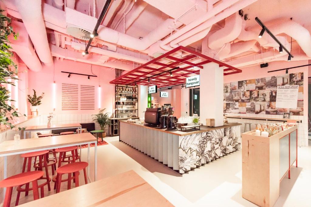 a restaurant with pink walls and red stools at Conscious Hotel Vondelpark in Amsterdam