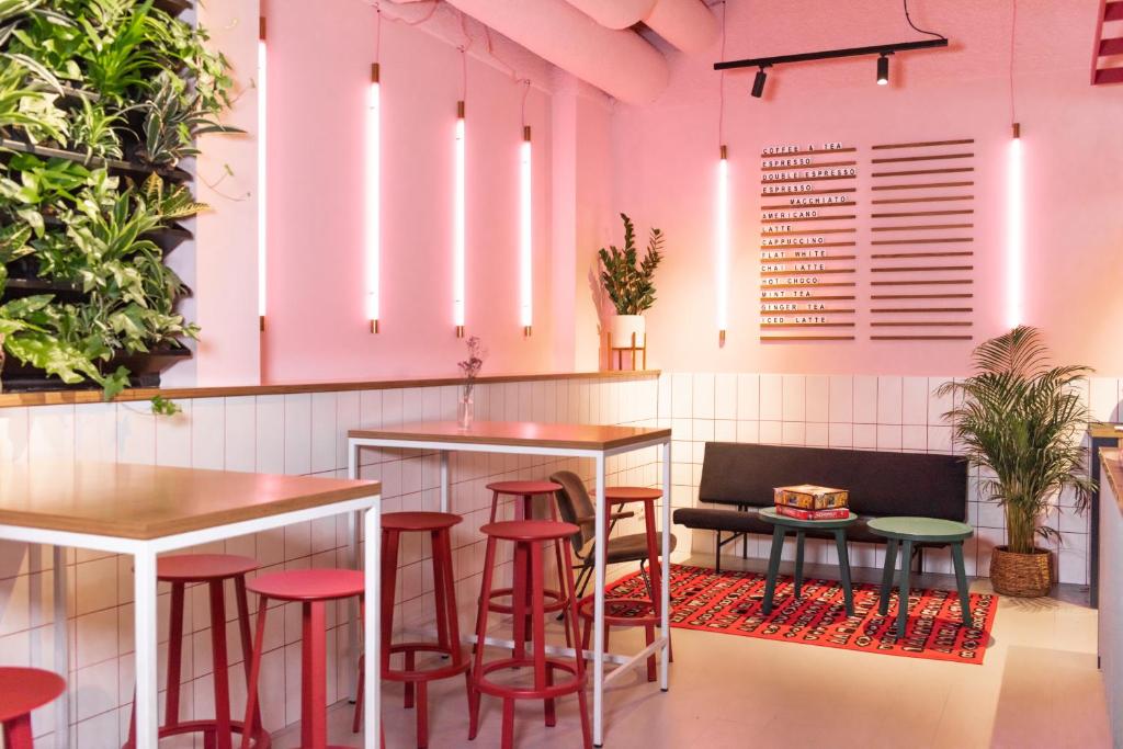 a restaurant with pink walls and red stools at Conscious Hotel Vondelpark in Amsterdam