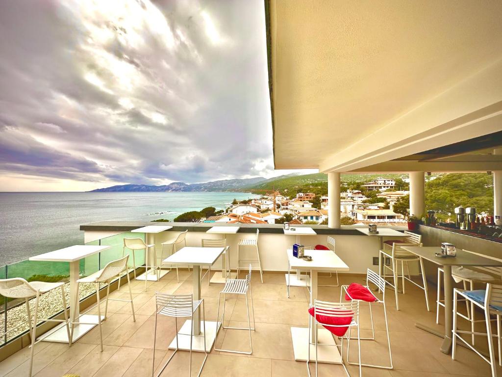 a restaurant with tables and chairs and a view of the water at Hotel Cala Luna in Cala Gonone
