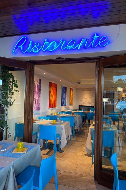a restaurant with blue tables and chairs and a sign at Hotel Cala Luna in Cala Gonone