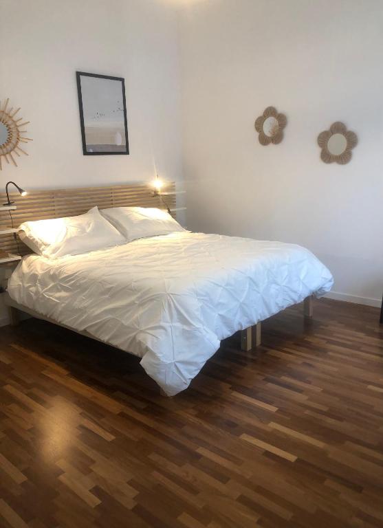 a bedroom with a bed with white sheets and a wooden floor at Casa de Mama in Trieste