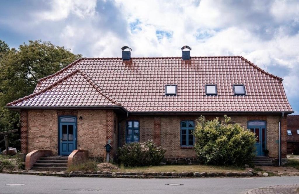 a brick house with a red roof and blue doors at Alte Schule Grambow - Lütt Slaapsteed in Grambow