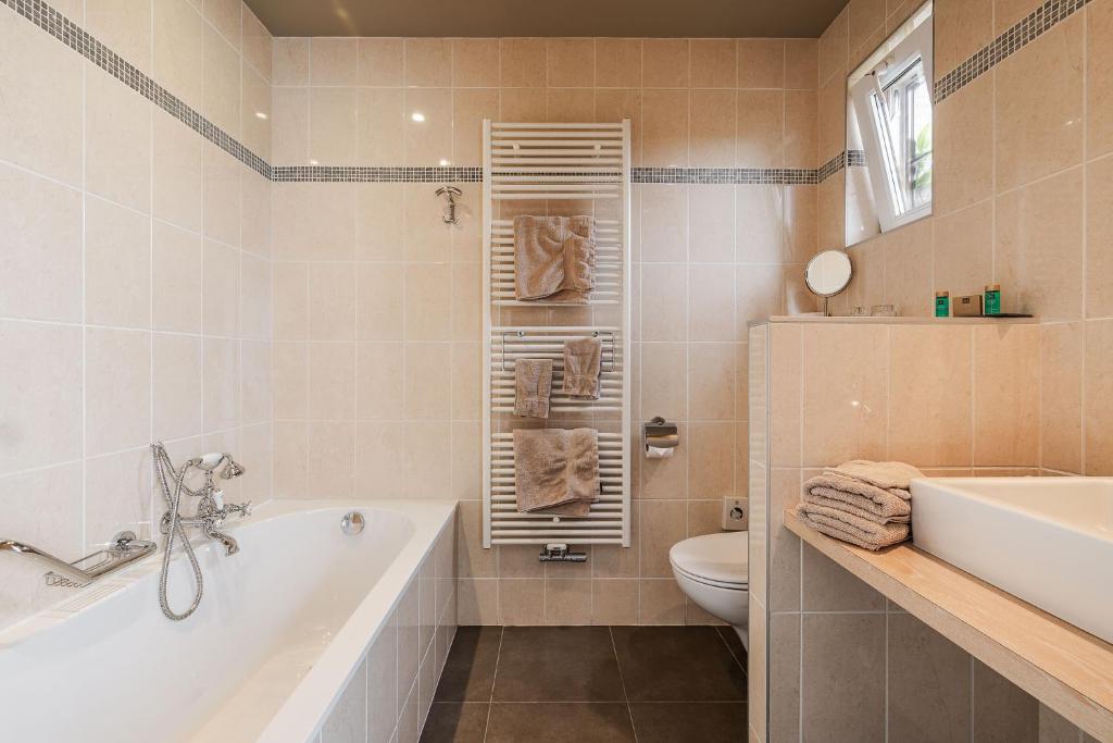 a bathroom with a tub and a toilet and a sink at Apollonia in Aalter