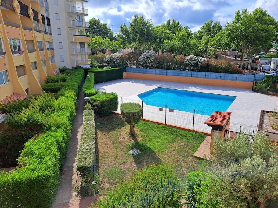 une vue aérienne d'une piscine dans un jardin dans l'établissement Le Sopraland 203, Joli T2 avec piscine et parking, au Cap d'Agde