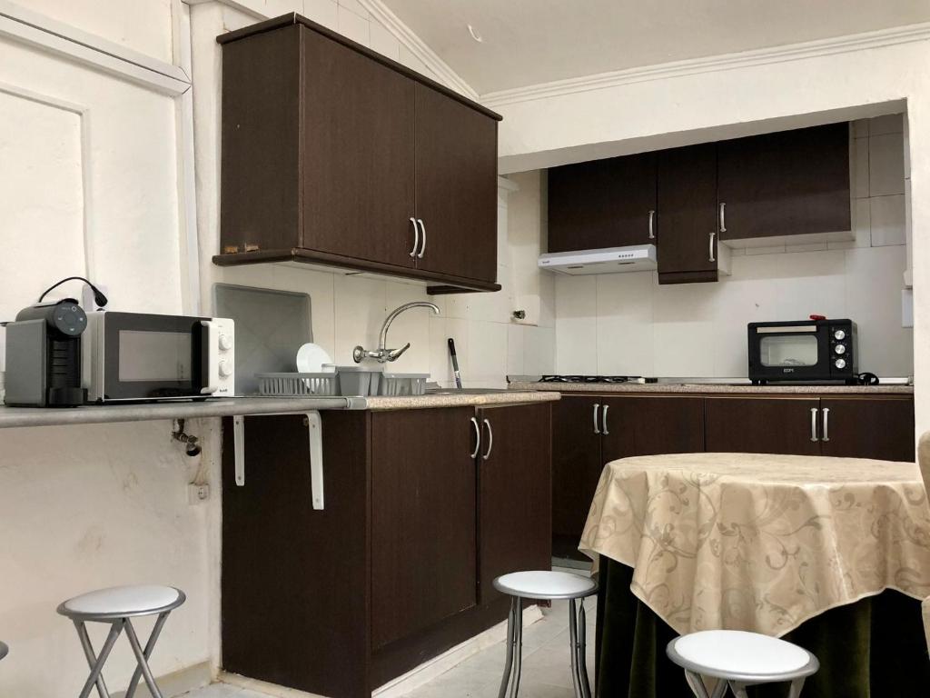 a kitchen with brown cabinets and a table with stools at Casa das Casas Novas - Beco das Avós in Elvas