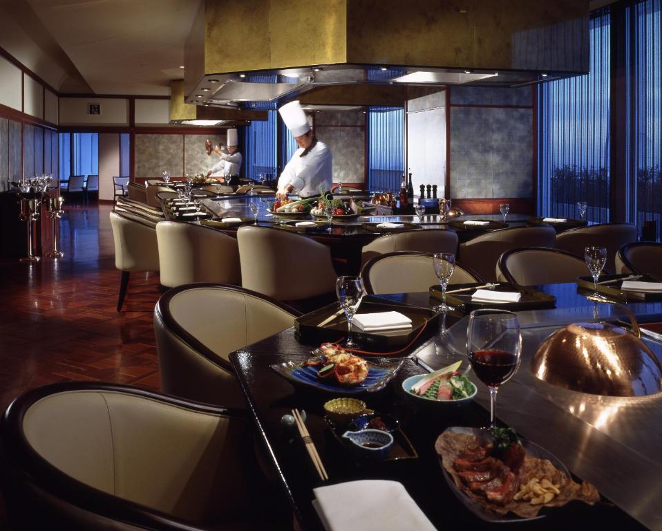 a restaurant with tables and a chef preparing food at Nagoya Marriott Associa Hotel in Nagoya