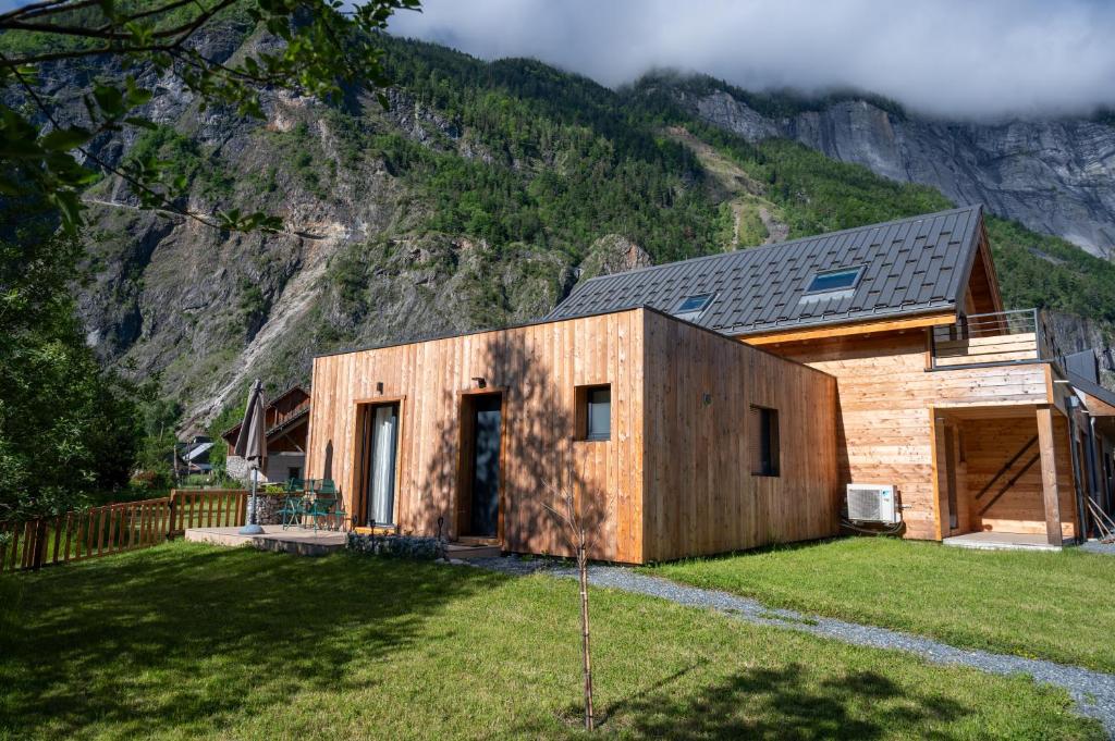 a wooden house in front of a mountain at L'escapade Oisans in Le Vert