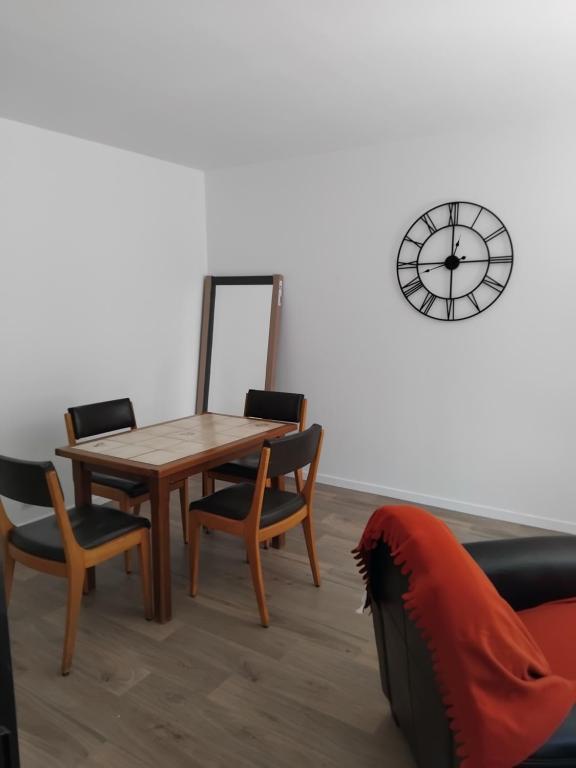 une salle à manger avec une table, des chaises et une horloge dans l'établissement Appartement bien situé, à Rennes