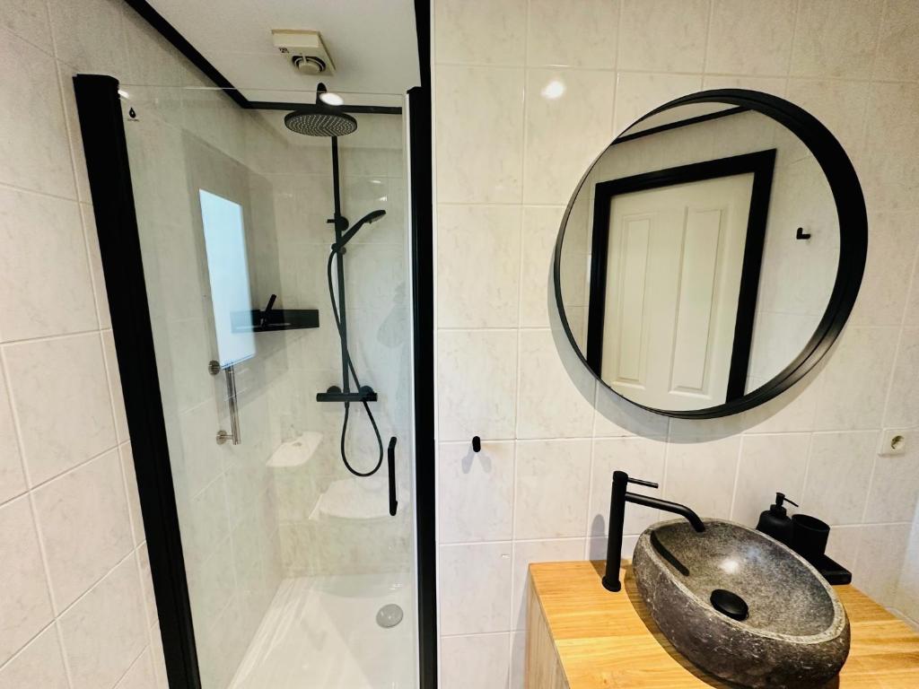 a bathroom with a sink and a mirror and a shower at StayatSas Tiny House Pippa in de bossen op de Veluwe in Doornspijk