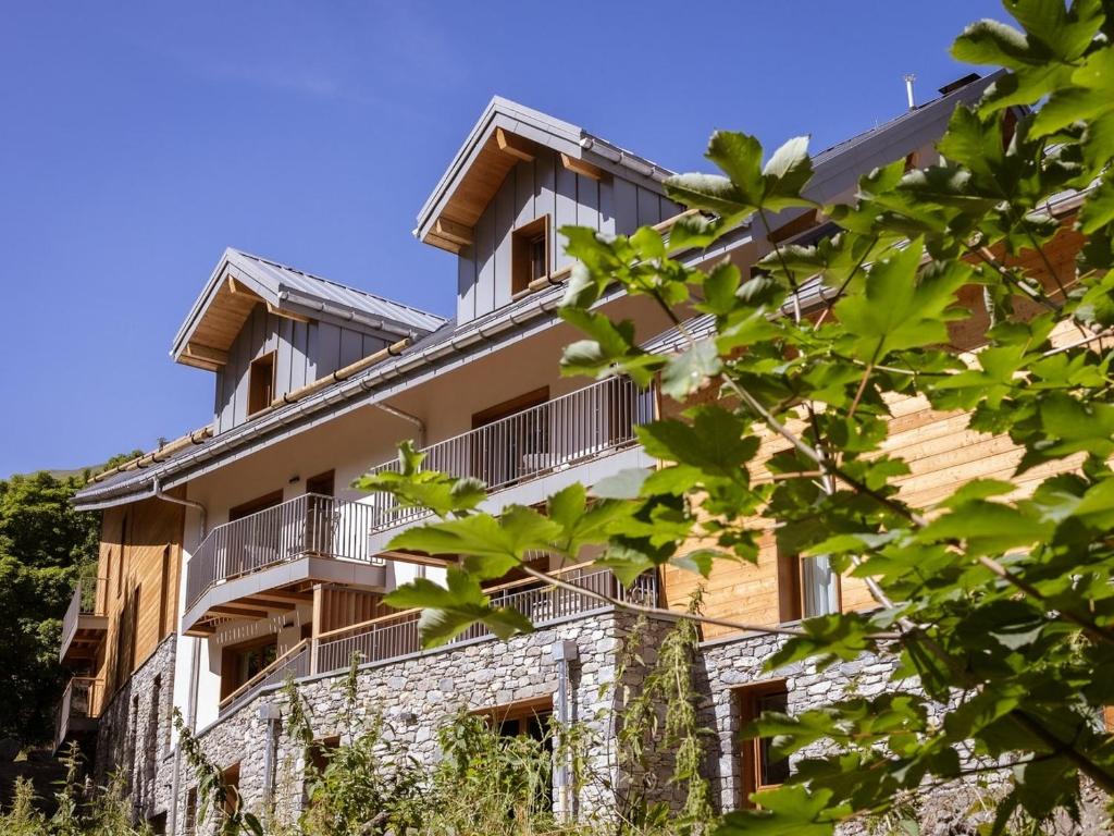 un immeuble d'appartements avec balcon et arbres dans l'établissement Résidence & Spa Les Cîmes d'Auréa, à Valloire