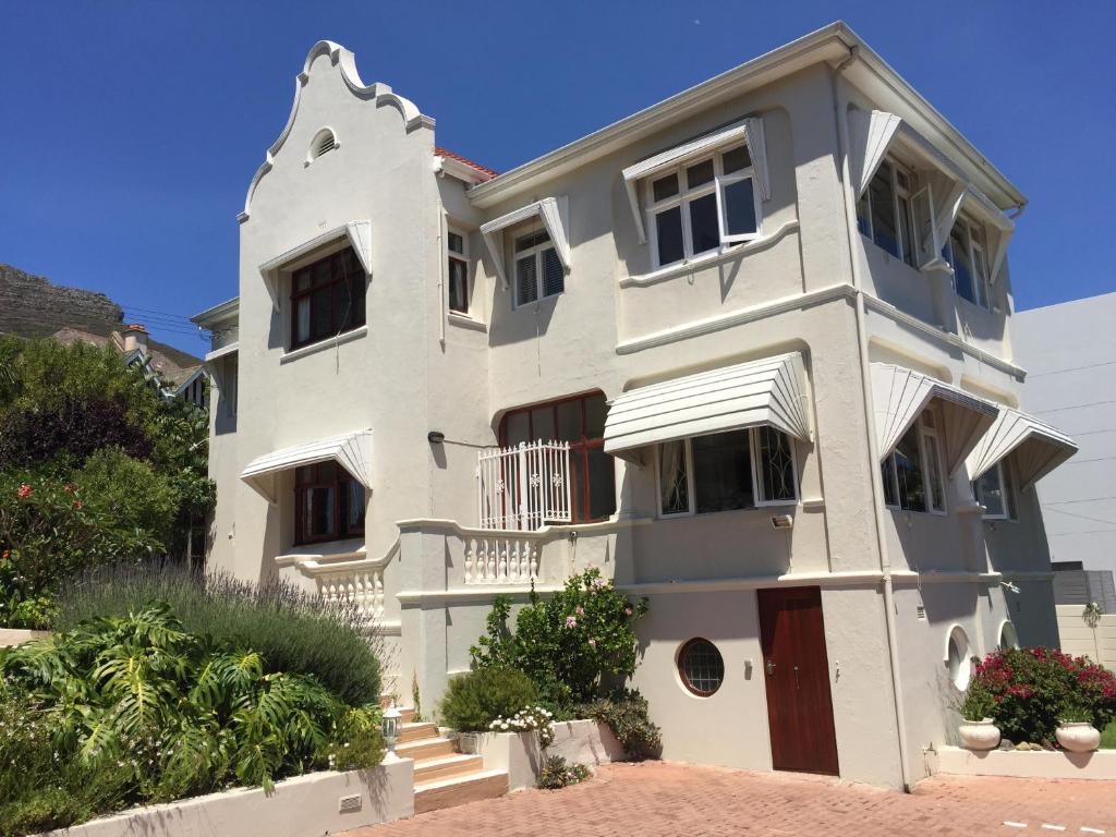 una casa blanca con piso Aveth en Villa Zeezicht, en Ciudad del Cabo
