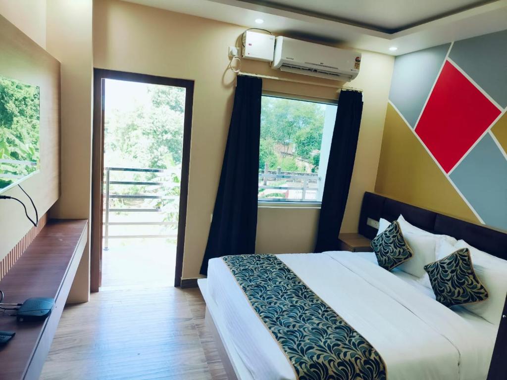 a bedroom with a bed and a large window at SAROJINI GARDEN HOTEL & RESTAURANT in Begusarai