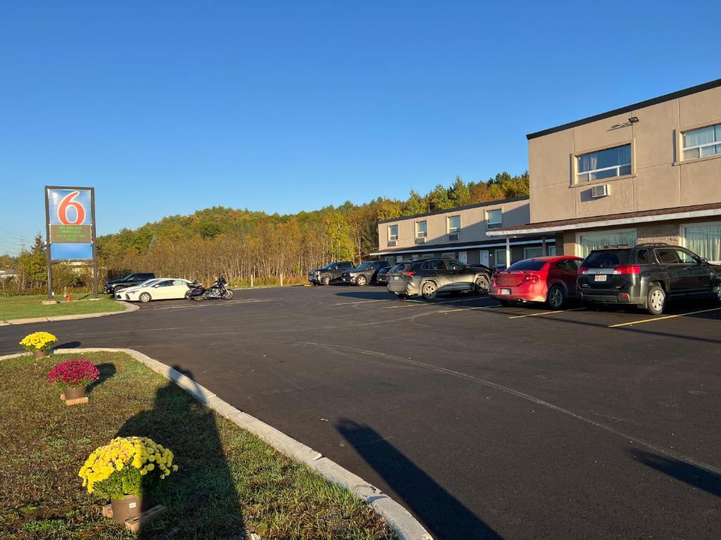 a parking lot with cars parked in front of a building at Motel 6-Sudbury, ON in Sudbury