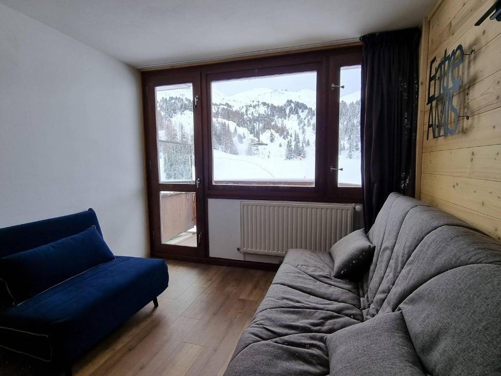 un salon avec un canapé et une grande fenêtre dans l'établissement Studio rénové cosy à Plagne Centre avec balcon, skis aux pieds - FR-1-351-176, à La Plagne Tarentaise
