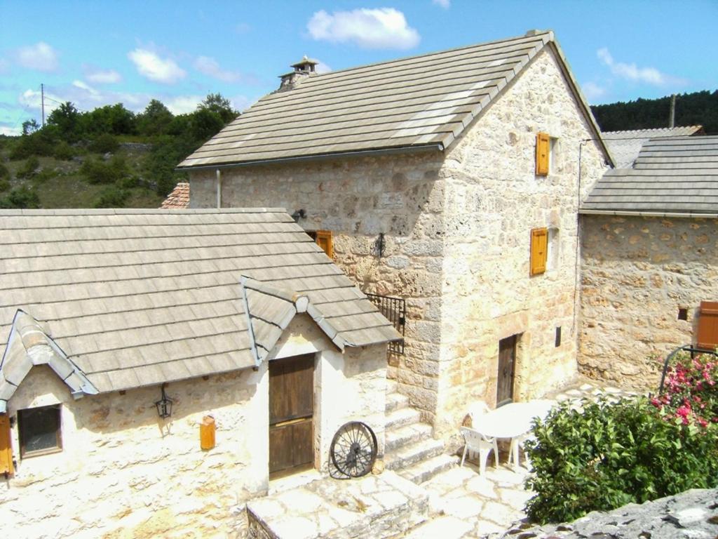 un grand bâtiment en pierre avec un toit avec un patio dans l'établissement La maison de malaury, à Laval-du-Tarn