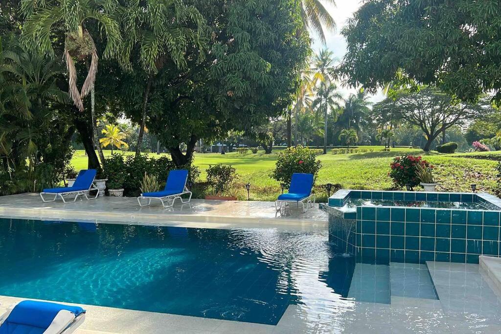 una piscina con due sedie blu e alberi di Vista Golf Luxury House a Girardot