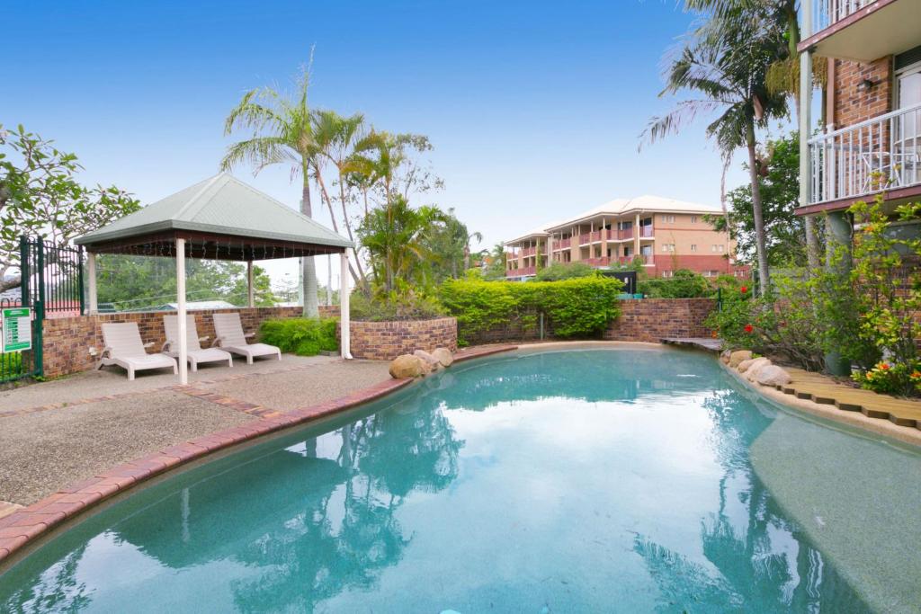 a swimming pool with a gazebo next to a building at Toowong Villas in Brisbane