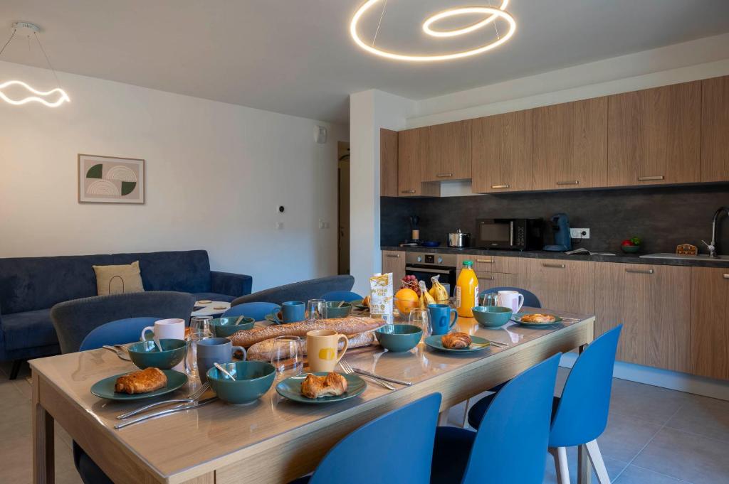 - une table en bois avec de la nourriture et des chaises bleues dans l'établissement Apartment Le Nid, aux Gets