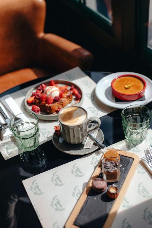 a table with plates of food and a cup of coffee at Hotel Belleval in Paris