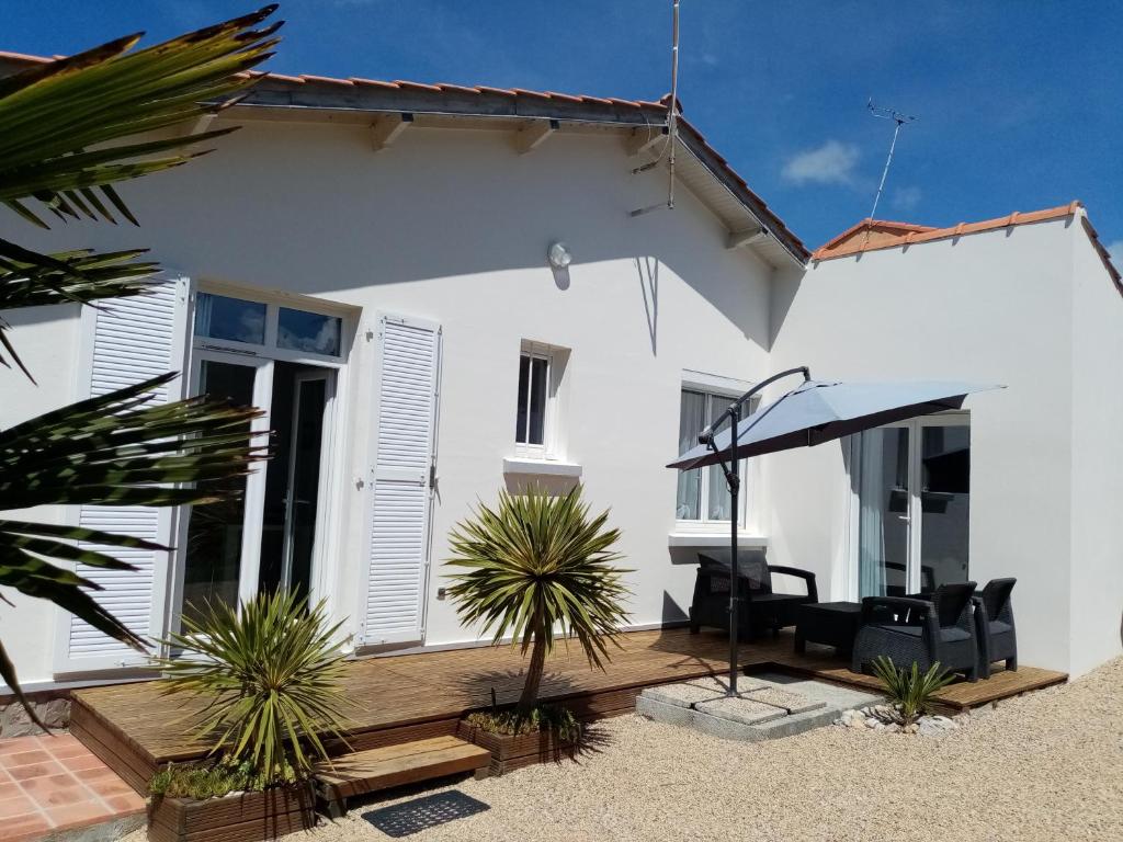 une maison blanche avec des chaises noires et un parasol dans l'établissement Evasion, à Pornic