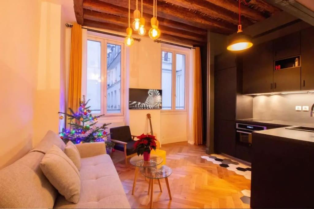 un salon avec un canapé blanc et une cuisine dans l'établissement Bel Appartement Parisien, TYPIQUE DU MARAIS, à Paris