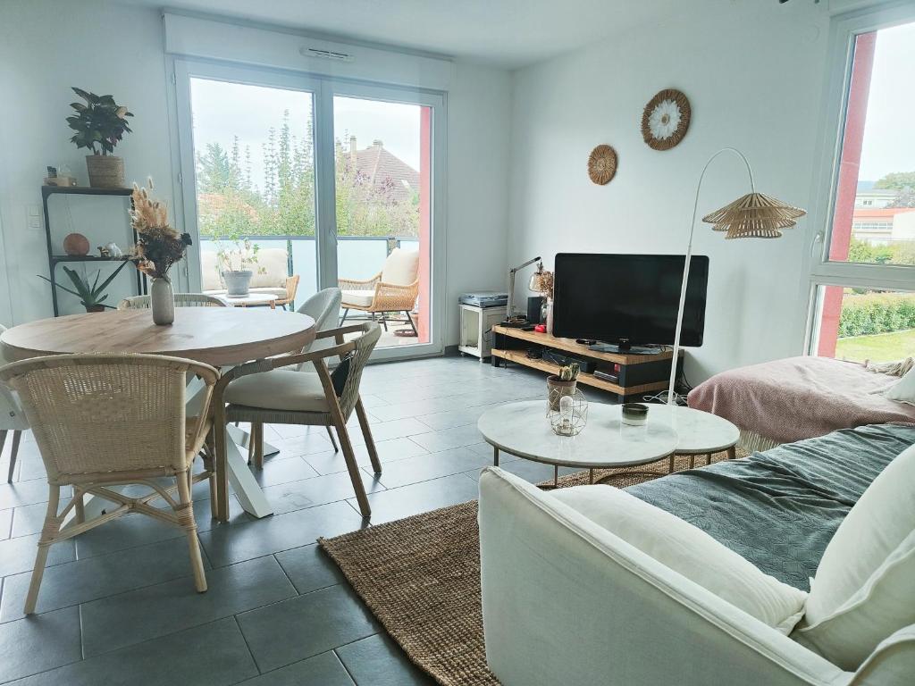 un salon avec une table et une télévision dans l'établissement Spacieux appartement lumineux, à Colmar