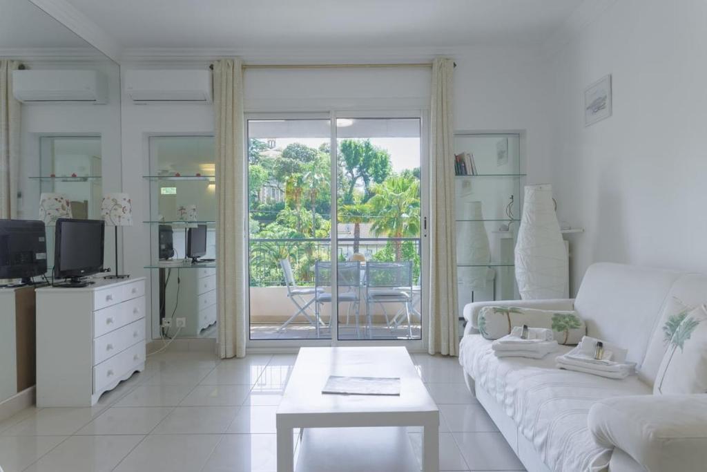 un salon blanc avec un canapé et une table dans l'établissement LE BELLA studio avec balcon idéal pour une évasion à deux, au calme et proche du centre-ville, à Cannes