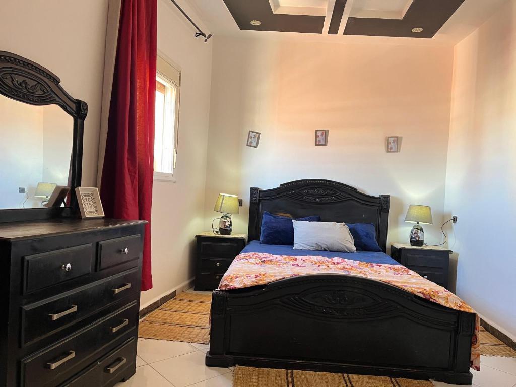 a bedroom with a black bed and a dresser at Modern Moroccan apartment near the beach in Safi in Safi