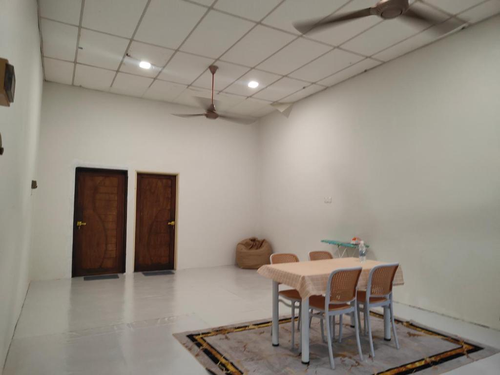 a table and chairs in a room with white walls at SS HOMESTAY - Homestay Budget Tanah Merah in Tanah Merah