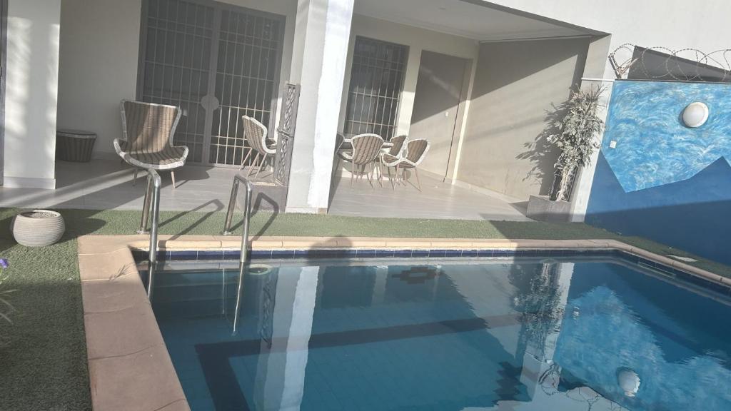 una piscina con sedie e una casa di VILLA AVEC PISCINE à NGAPAROU à 1 MIN DE LA PLAGE A PIED a Ngaparou
