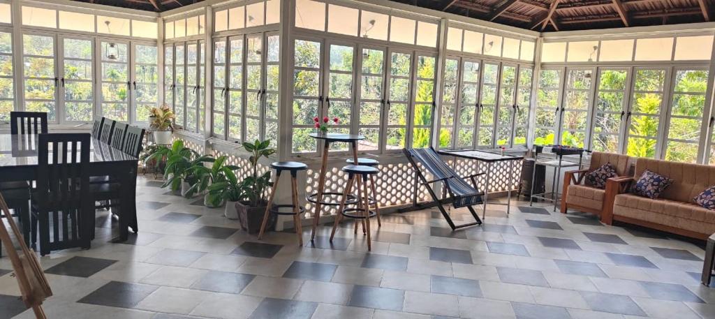 a conservatory with tables and chairs in a room with windows at PADIKKAL BUNGLOW in Vayittiri
