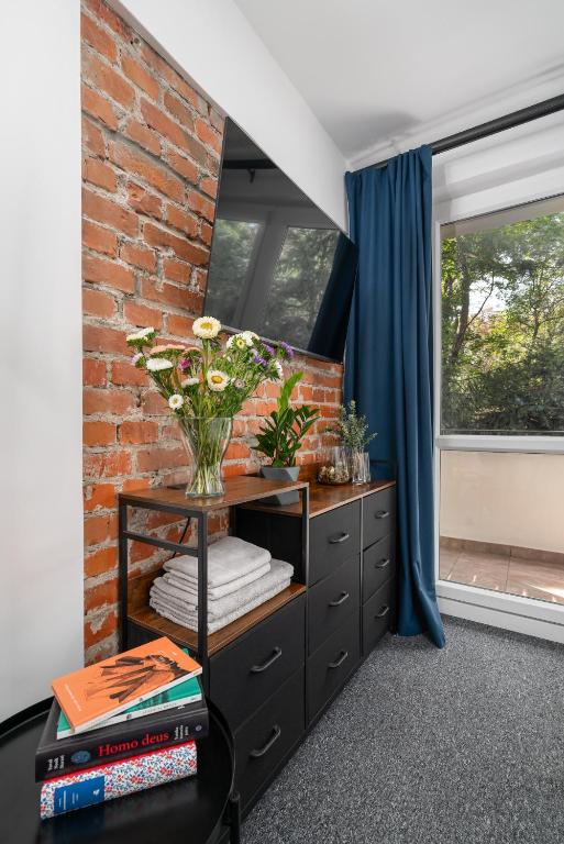 a room with a brick wall and a vase with flowers at Patro Apartament 2 Wrocław Centrum in Wrocław
