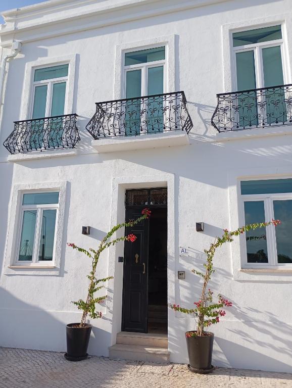 a white building with two potted plants in front of a door at Villa Sado in Alcácer do Sal