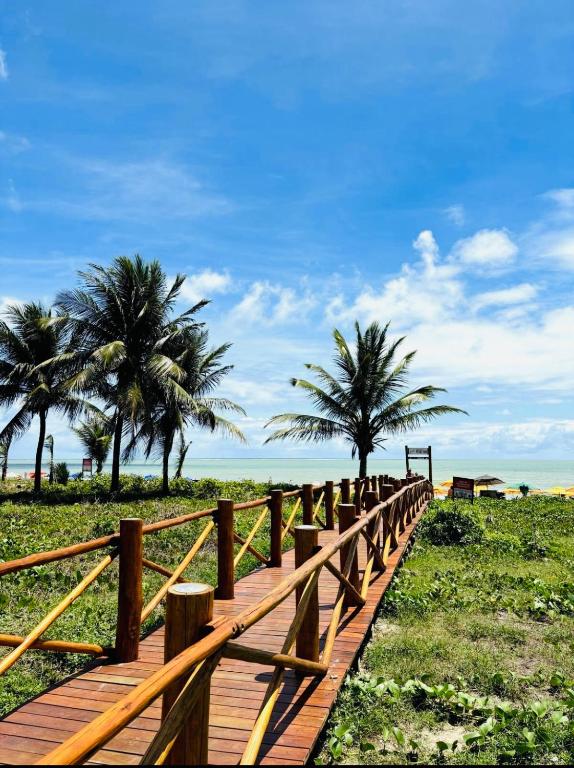 a wooden boardwalk leading to the beach with palm trees at Reserva 1202 - Hospedagem in Cabedelo