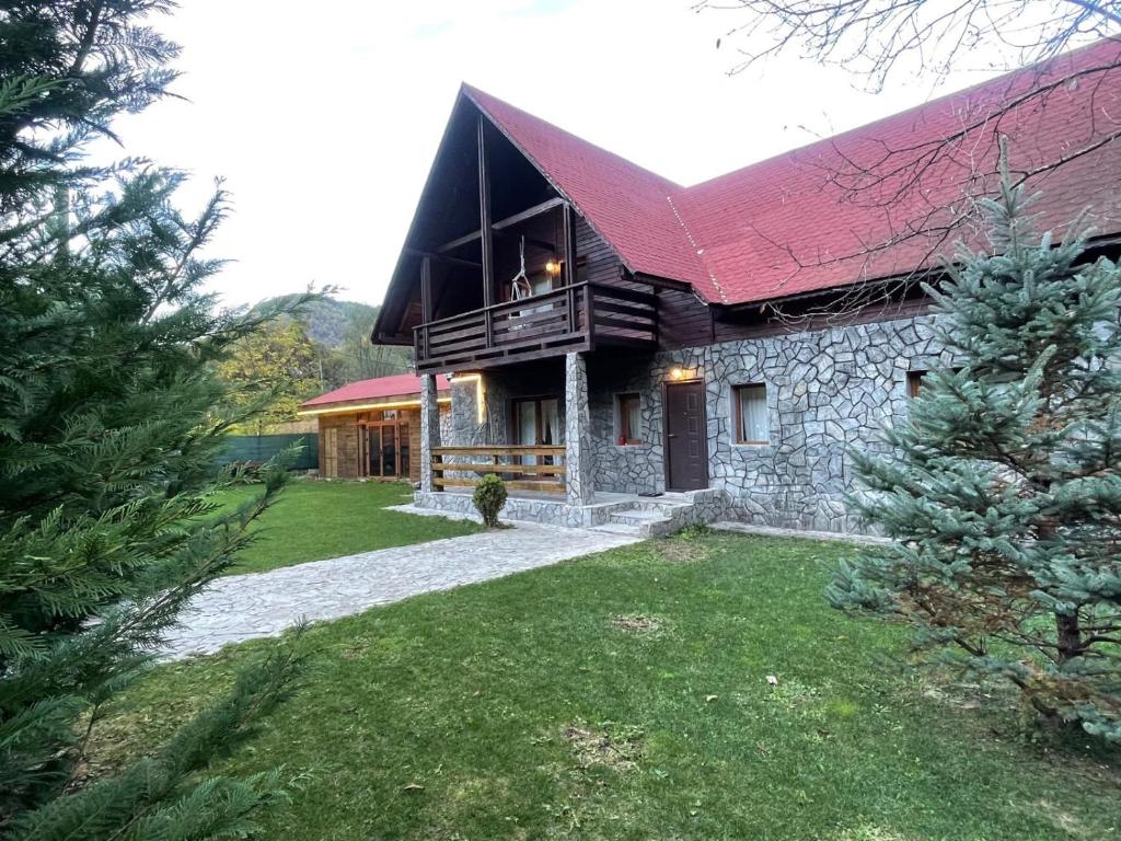 una gran casa de piedra con techo rojo en Casa Rosso, en Valea Măceşului
