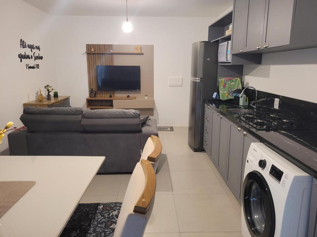 a kitchen and living room with a couch and a stove at Apto Belle Residencial Ilha Bela in Passo de Torres