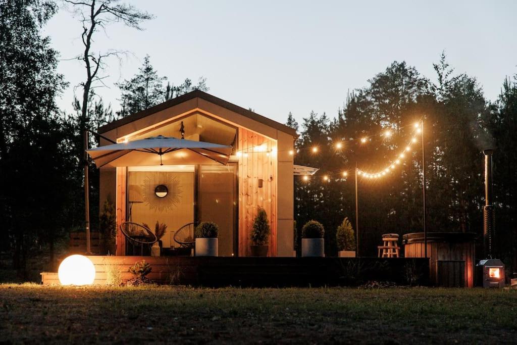 a small house with an umbrella and lights at Vienis glamping - cozy and private forest house in Randamonys