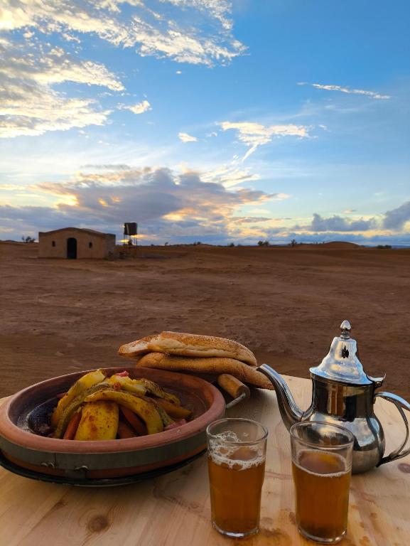 un vassoio di cibo su un tavolo con una teiera e un piatto di banane di Silent Camp a M'Hamid