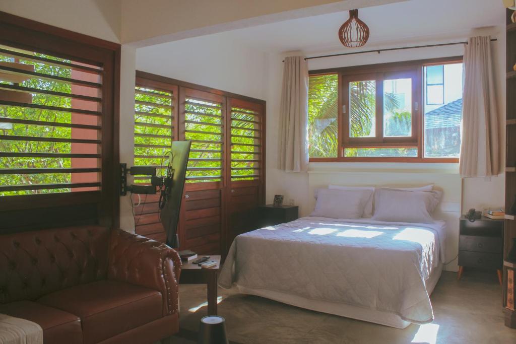 a bedroom with a bed and a couch and windows at Naquela Casa Jericoacoara in Jericoacoara