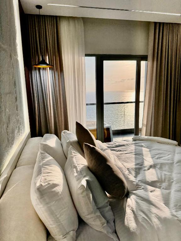 a bedroom with a white bed with pillows and a window at Damac Apartment شقة مع جاكوزي بإطلالة بحرية in Jeddah
