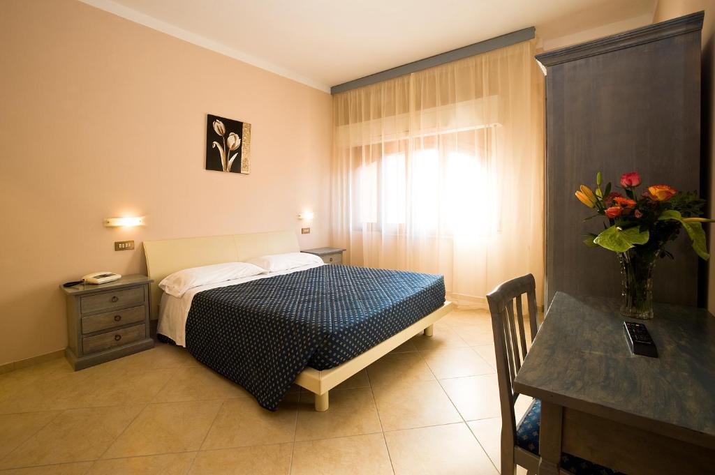 Un dormitorio con una cama y un jarrón de flores. en Villa Hotel Del Sole, en Chiusi