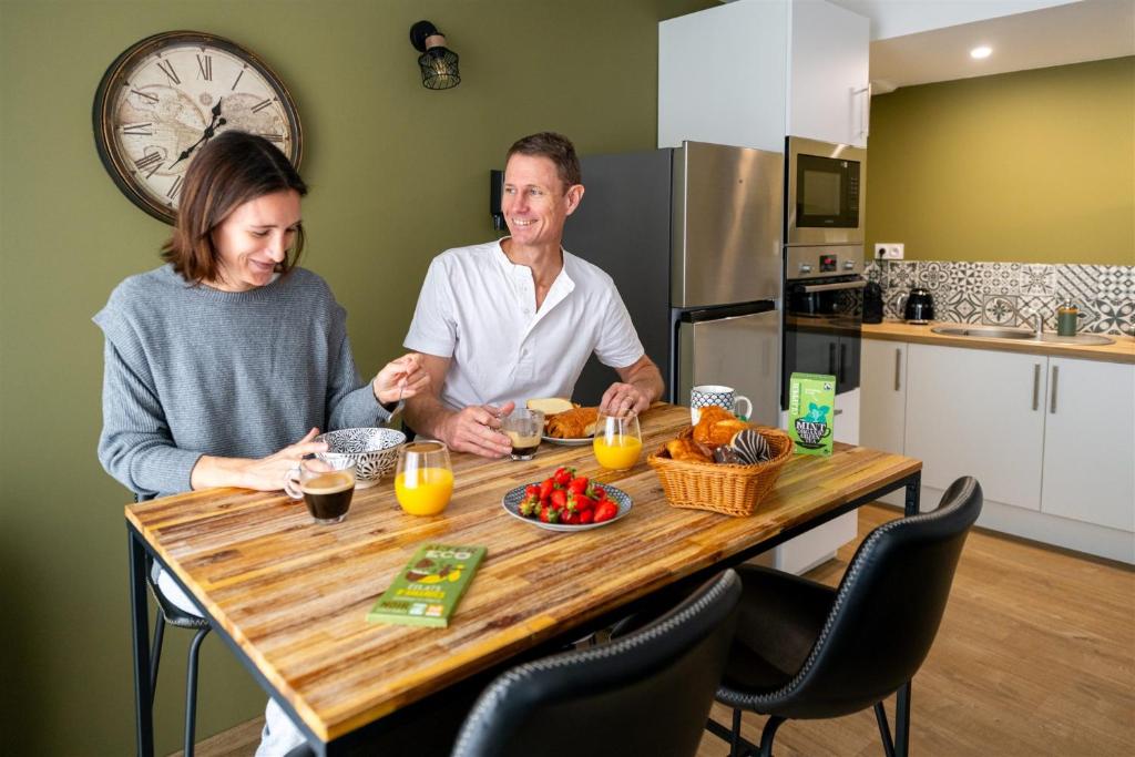 un homme et une femme assis à une table avec de la nourriture dans l'établissement Espace, confort, calme et design en plein centre !, à Laval