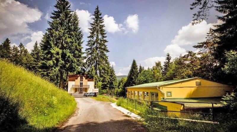 a house on a dirt road next to a forest at Horský Hotel Magura in Chvojnica