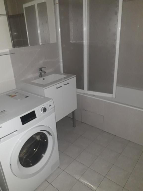 - un lave-linge blanc dans la salle de bains pourvue d'un lavabo dans l'établissement Grand studio cosy, lumineux et équipé au cœur du Chesnay, à Le Chesnay