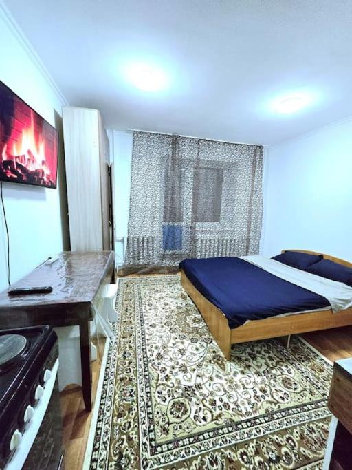 a bedroom with a bed and a table and a rug at Астана аэропорт студия in Prigorodnyy
