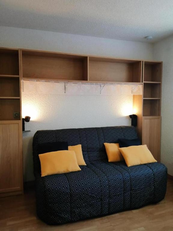 un salon avec un canapé noir avec des coussins jaunes dans l'établissement Résidence Le Chanteloup - Joli studio sur les pistes ! MAE-9284, à Aime La Plagne