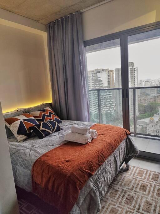 a bedroom with a bed and a large window at On Paulista - Confort Studio in São Paulo