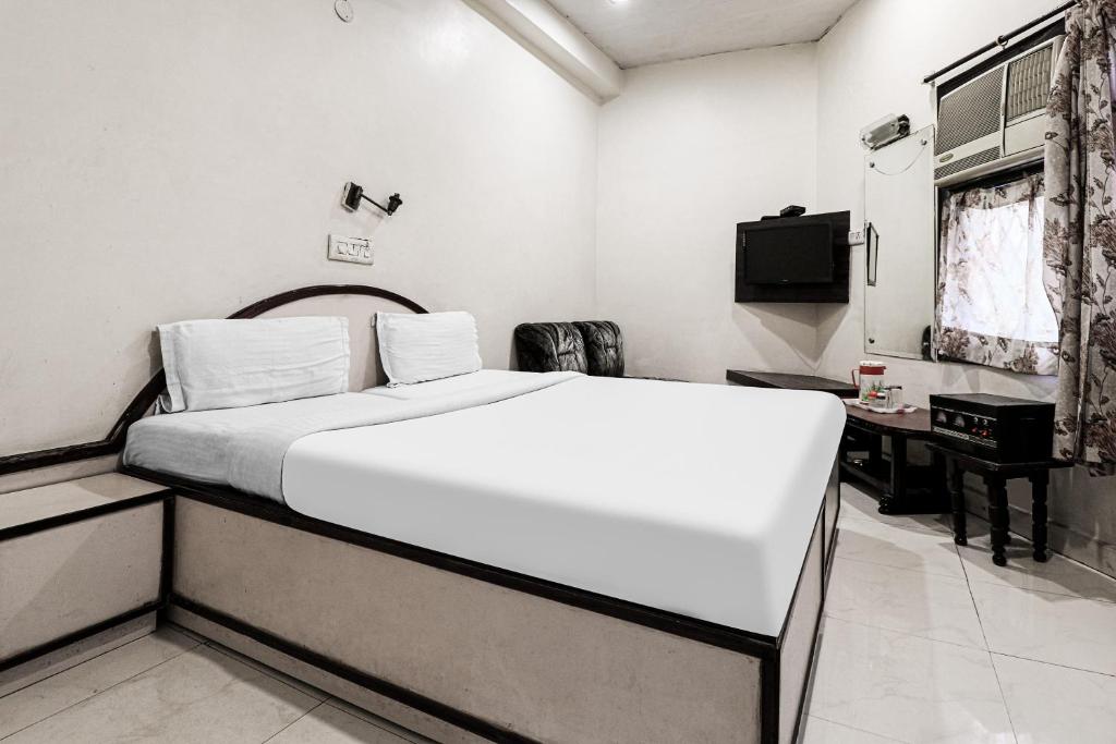 Un dormitorio con una gran cama blanca y un escritorio. en Hotel O Surya, en Ludhiana